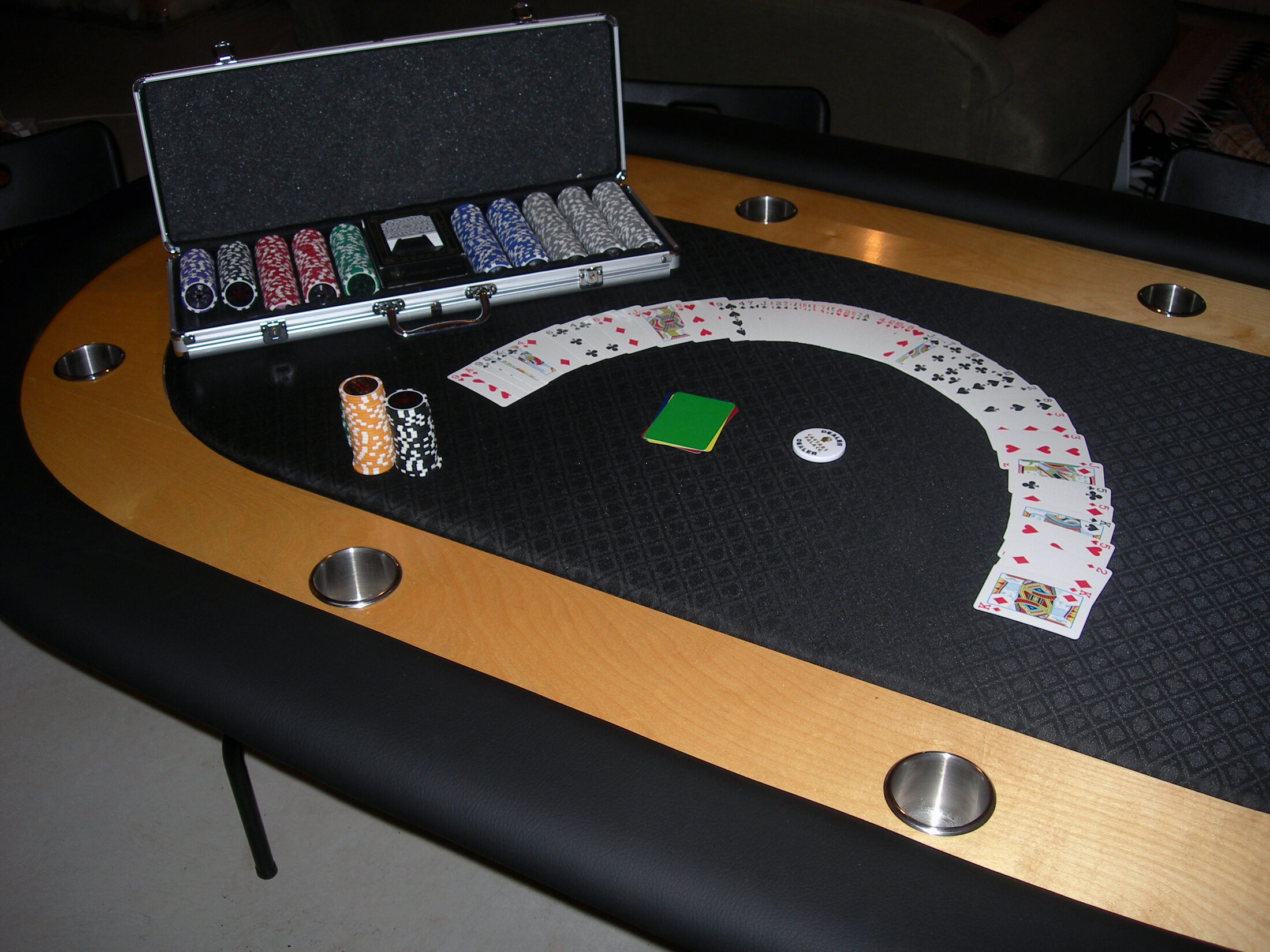 Finished eight-player DIY racetrack poker table with padded vinyl rails, hardwood chip raceway, stainless cup holders, and black suited speed cloth
