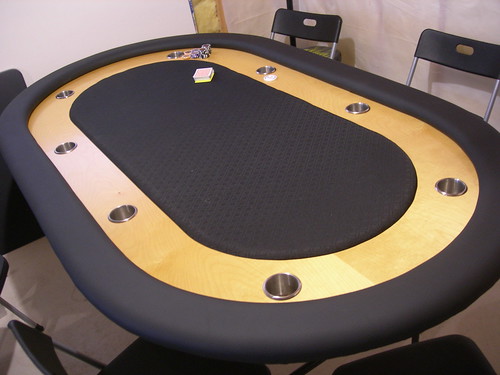 Three-quarter view of finished racetrack poker table with black rails and wood raceway