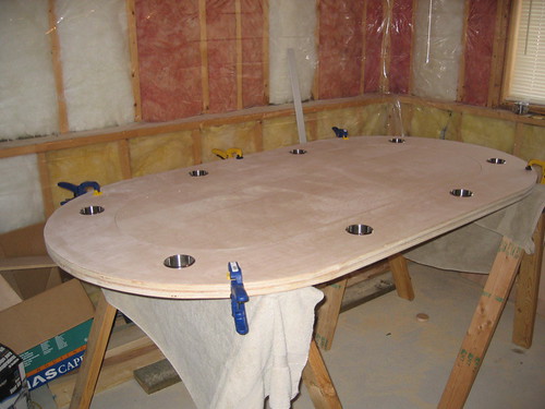 Oval plywood raceway on sawhorses with stainless cup holders dry-fitted into the ring